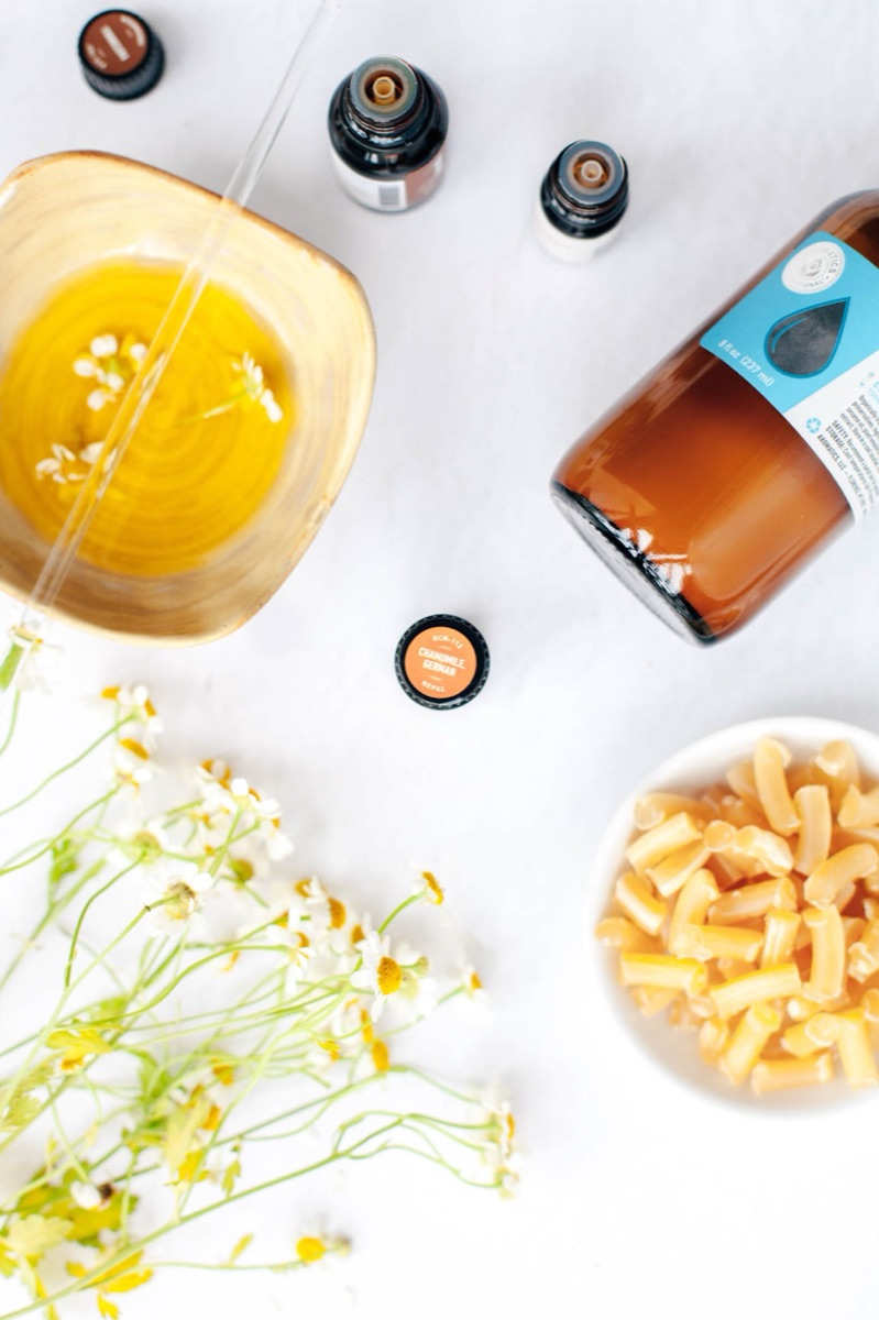 Essential oils, a carrier, and botanicals laid out for a blend in progress